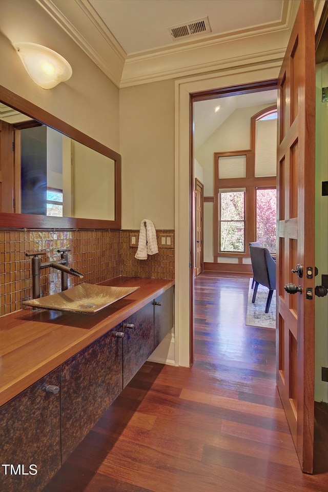 805 Greenwood Rd, Chapel Hill, NC 27514 - bathroom with crown molding, visible vents, wood finished floors, a sink, and backsplash