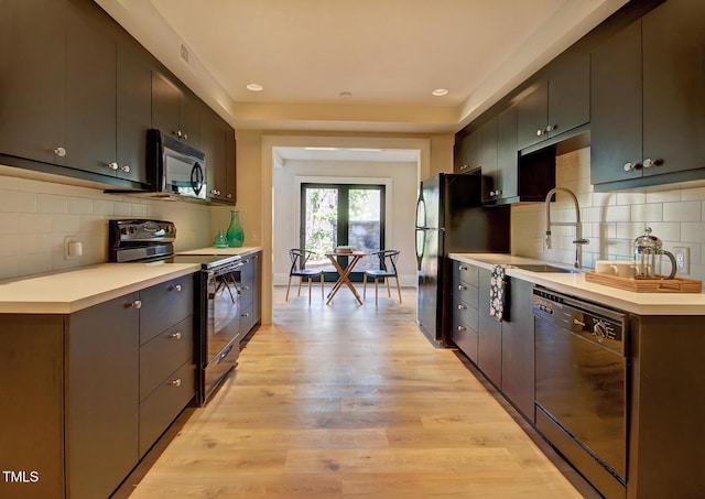 805 Greenwood Rd, Chapel Hill, NC 27514 - kitchen featuring light wood-type flooring, decorative backsplash, light countertops, and black appliances