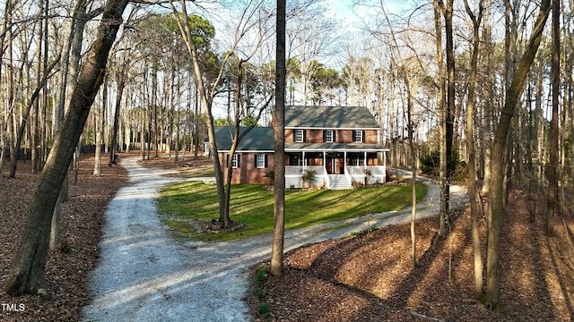 view of front of property with brick siding, driveway, and a front yard