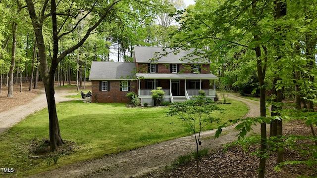 colonial home featuring dirt driveway, a front yard, and covered porch