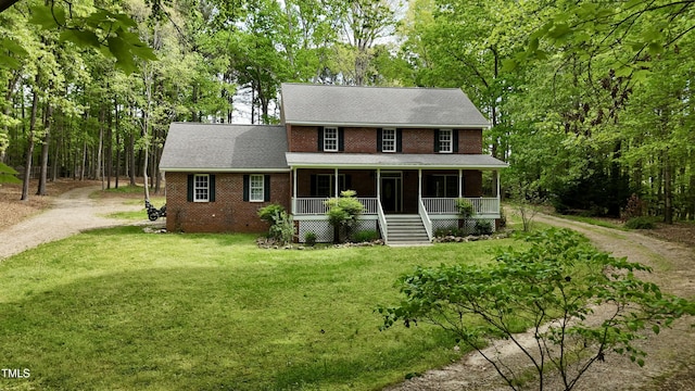 view of front of home featuring roof with shingles, a front lawn, driveway, covered porch, and brick siding
