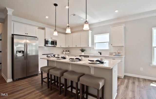 kitchen featuring a breakfast bar area, a kitchen island, stainless steel appliances, white cabinetry, and crown molding