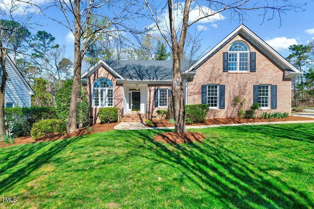 traditional-style house featuring brick siding and a front lawn