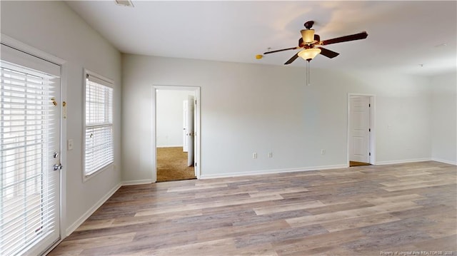 spare room with light wood-type flooring, baseboards, and ceiling fan