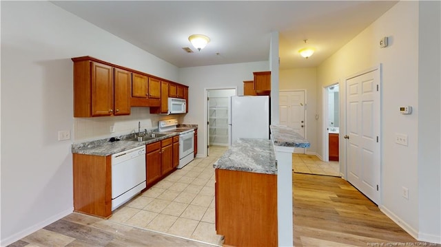 kitchen featuring white appliances, baseboards, backsplash, and a sink