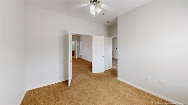 unfurnished bedroom featuring a ceiling fan, light colored carpet, and baseboards