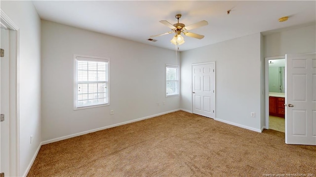 unfurnished bedroom featuring baseboards, visible vents, ceiling fan, carpet flooring, and connected bathroom