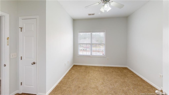 carpeted spare room featuring baseboards, visible vents, and ceiling fan