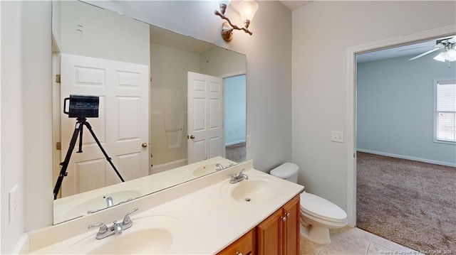 full bath with double vanity, toilet, a ceiling fan, and a sink