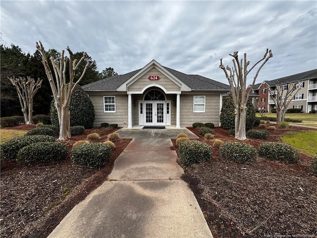 view of front of home featuring french doors and roof with shingles