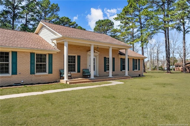 view of front of property with brick siding, covered porch, a front yard, and roof with shingles