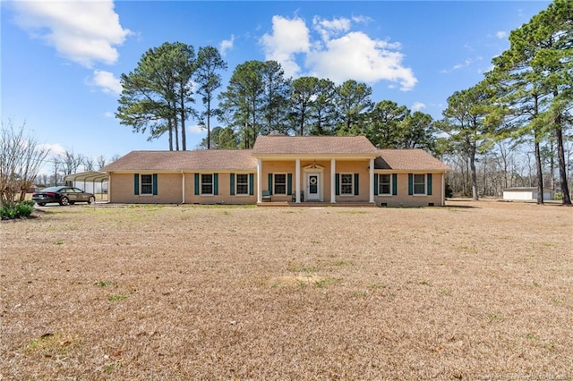 single story home with a detached carport, covered porch, and a front yard