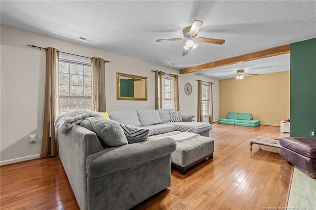 living room featuring visible vents, baseboards, hardwood / wood-style flooring, a textured ceiling, and a ceiling fan