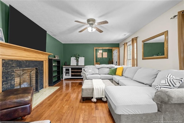 living area featuring a fireplace, a ceiling fan, and wood finished floors