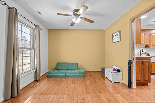 living area with baseboards, visible vents, a wealth of natural light, and light wood-type flooring