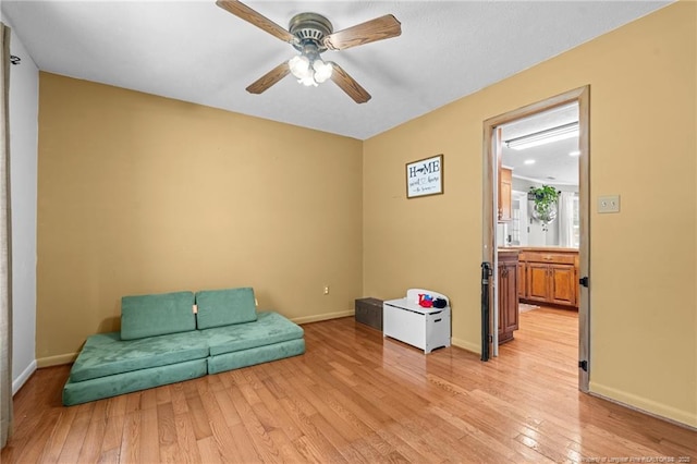 living area with light wood-style flooring, baseboards, and ceiling fan