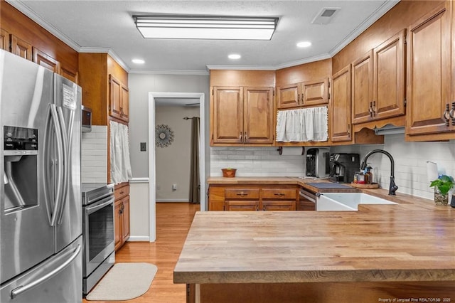 kitchen featuring wooden counters, stainless steel refrigerator with ice dispenser, wall oven, and a sink