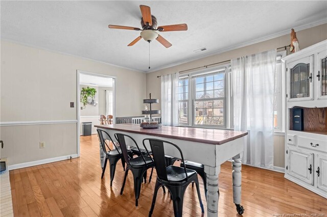 dining room with ceiling fan, visible vents, light wood-type flooring, and ornamental molding