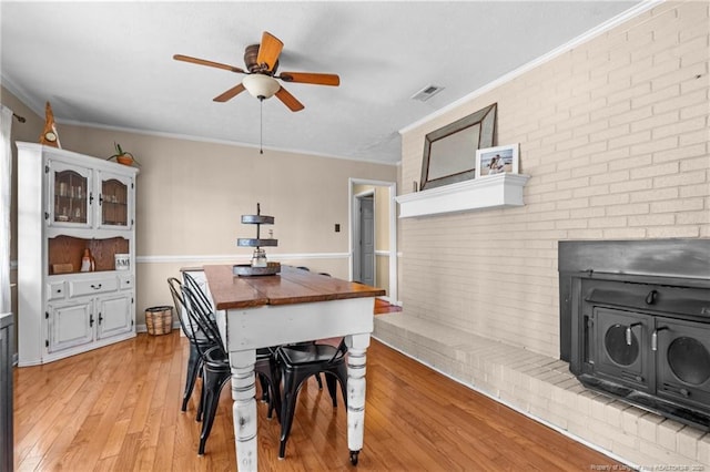 dining area with a ceiling fan, light wood-style floors, visible vents, and ornamental molding