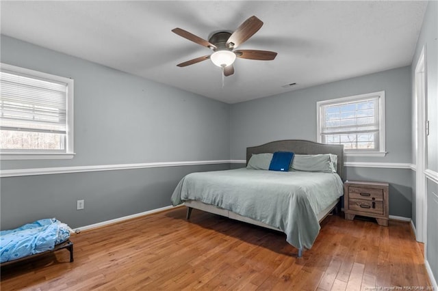 bedroom with multiple windows, visible vents, baseboards, and wood-type flooring