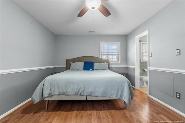 bedroom with visible vents, connected bathroom, baseboards, and hardwood / wood-style flooring