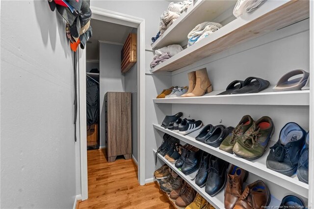 walk in closet with light wood-style floors