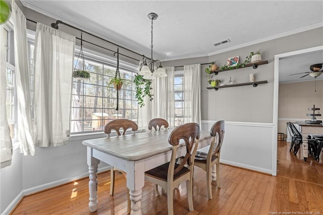 dining area featuring visible vents, ornamental molding, and wood finished floors