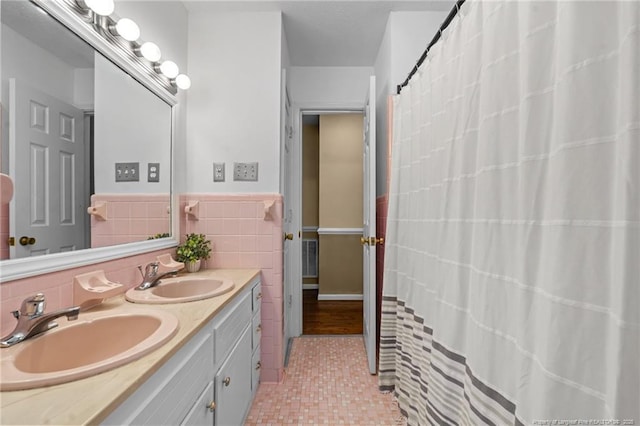 bathroom featuring double vanity, a wainscoted wall, tile walls, and a sink