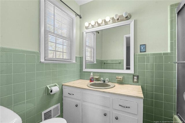 full bathroom featuring visible vents, vanity, toilet, and tile walls