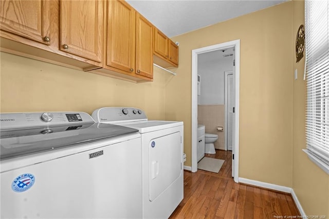 laundry room featuring wood finished floors, baseboards, cabinet space, separate washer and dryer, and tile walls