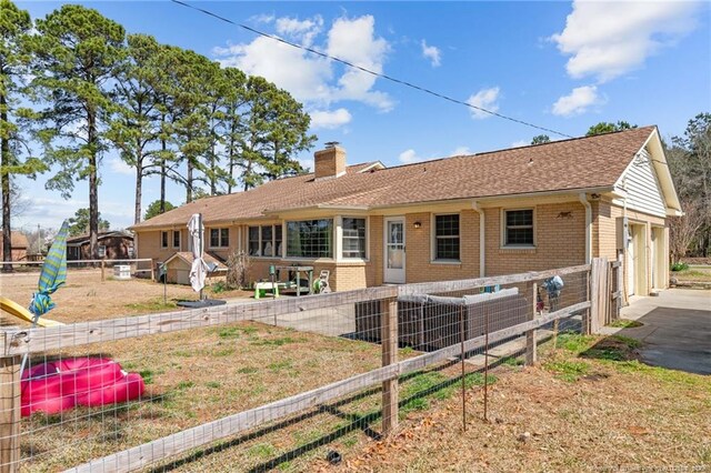 back of property with a garage, fence, brick siding, and a chimney