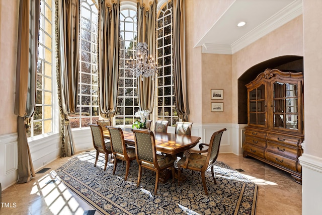 2421 Acanthus Dr, Wake Forest, NC 27587 - dining room with a decorative wall, crown molding, a wainscoted wall, a high ceiling, and arched walkways