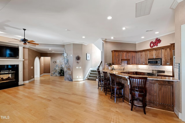 2421 Acanthus Dr, Wake Forest, NC 27587 - kitchen featuring appliances with stainless steel finishes, ornamental molding, backsplash, a sink, and a kitchen bar