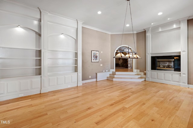2421 Acanthus Dr, Wake Forest, NC 27587 - unfurnished living room with wood finished floors, built in features, a glass covered fireplace, ornamental molding, and recessed lighting