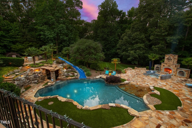 2421 Acanthus Dr, Wake Forest, NC 27587 - pool at dusk with an outdoor stone fireplace, a patio area, and an outdoor pool