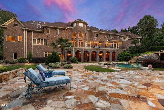 2421 Acanthus Dr, Wake Forest, NC 27587 - back of property at dusk with a patio, brick siding, a balcony, and a pool with connected hot tub