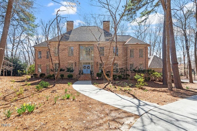 georgian-style home featuring brick siding and a chimney