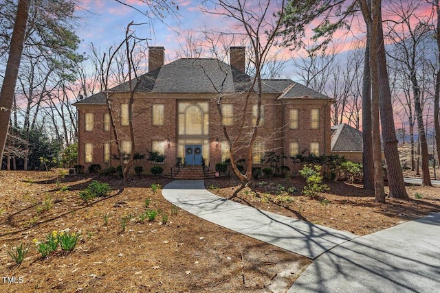 view of front facade with brick siding and a chimney