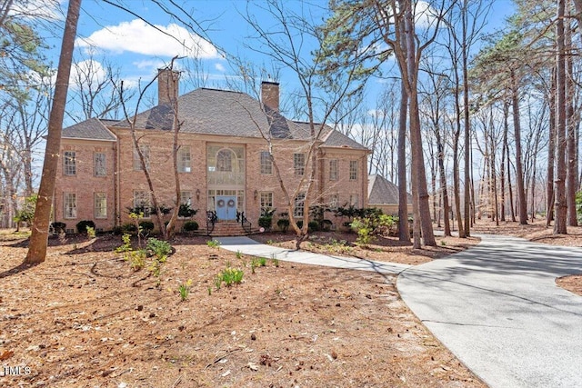 view of front facade with driveway and a chimney