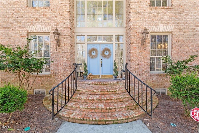 doorway to property featuring brick siding, visible vents, french doors, and crawl space