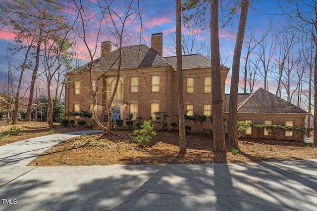 property exterior at dusk featuring driveway and a chimney