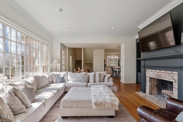 living area featuring recessed lighting, wood finished floors, ornamental molding, and a fireplace with flush hearth