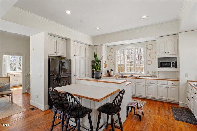 kitchen featuring built in microwave, white cabinets, a kitchen breakfast bar, and a center island