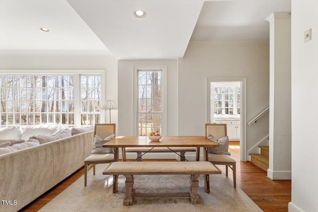 dining room with stairs, crown molding, plenty of natural light, and wood finished floors