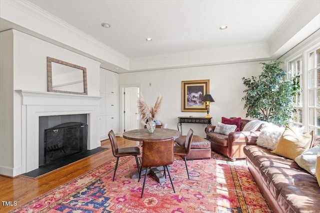 living area with recessed lighting, wood finished floors, ornamental molding, and a fireplace