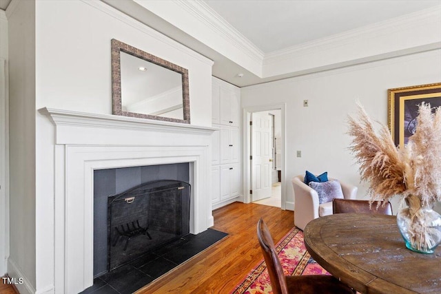 dining space featuring a fireplace, wood finished floors, and ornamental molding