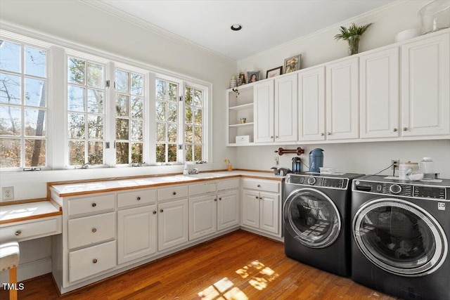 washroom with crown molding, light wood-style flooring, cabinet space, and washer and clothes dryer