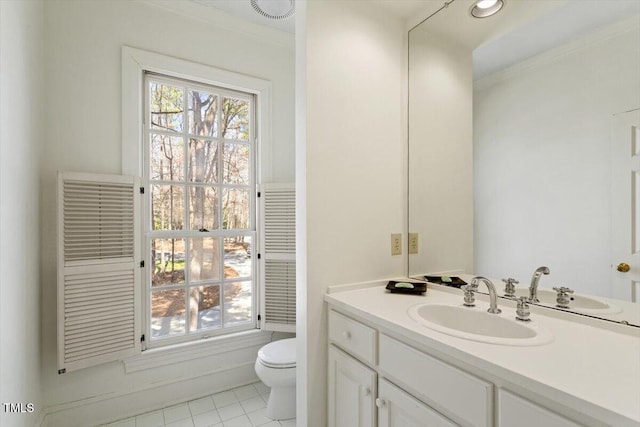 half bathroom with tile patterned floors, a healthy amount of sunlight, toilet, and vanity