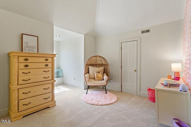 sitting room with lofted ceiling, visible vents, and light carpet