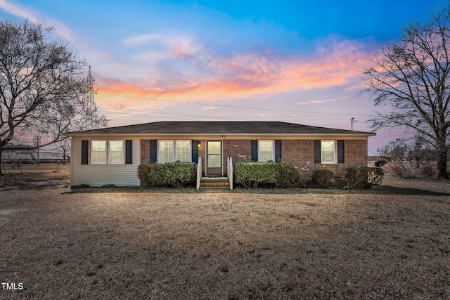 single story home featuring brick siding and a yard